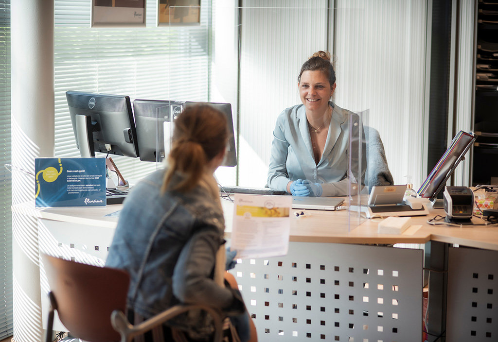 A Fluvius employee explains to a customer in a customer office