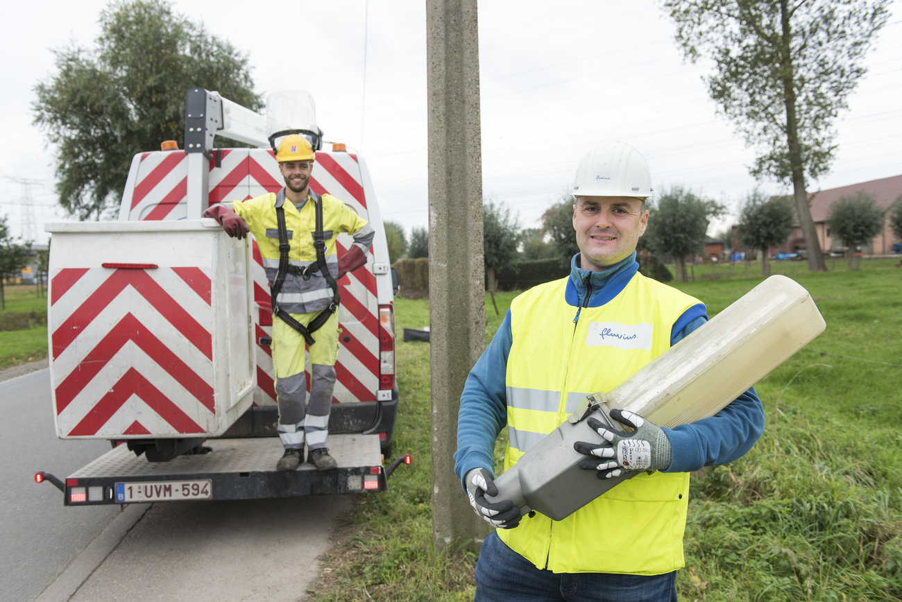 Medewerker van Fluvius houdt oude openbare verlichtingsarmatuur vast