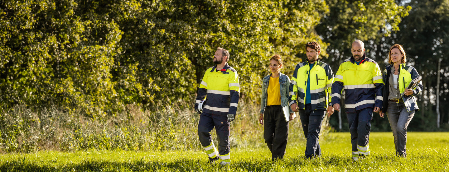 Medewerkers van Fluvius wandelen in een veld